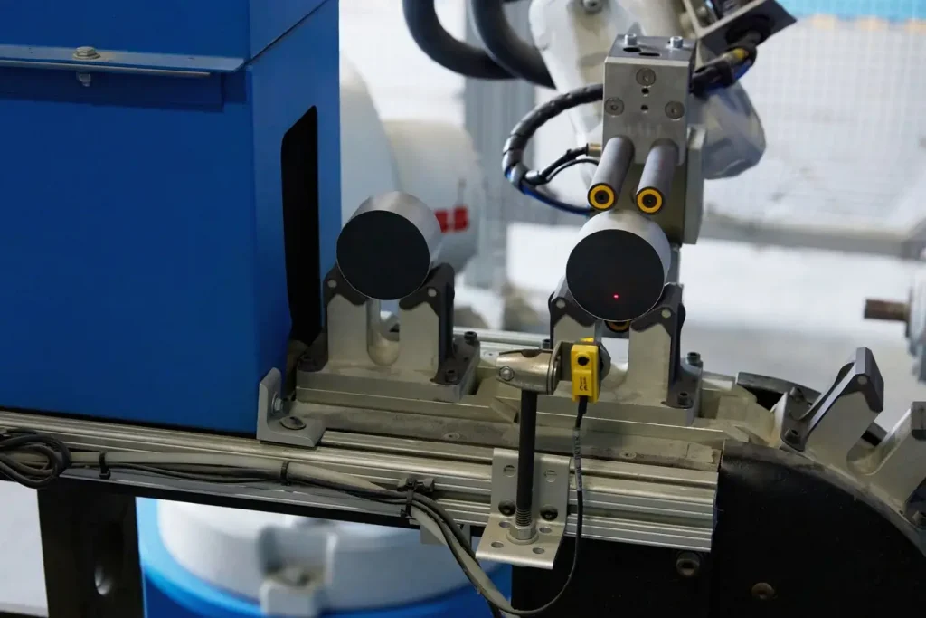 Dụng cụ cuối cánh tay robot (EOAT) này nhặt các MOV từ băng chuyền này và di chuyển chúng sang băng chuyền khác khi chúng đi vào trạm kim loại hóa. EOAT có thể bị mòn và in lại hàng loạt trên Dòng cầu chì là phương pháp thay thế dễ dàng nhất và ít tốn kém nhất.